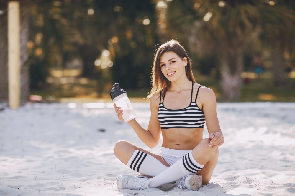 young and beautiful girl athlete poses for photos holding a shaker
