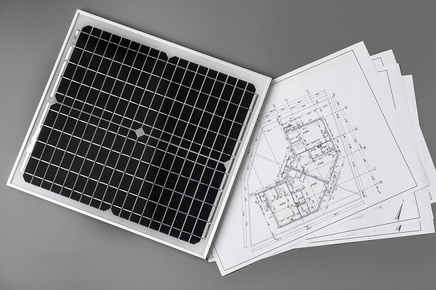 Architectural blueprints and solar panel on table close up