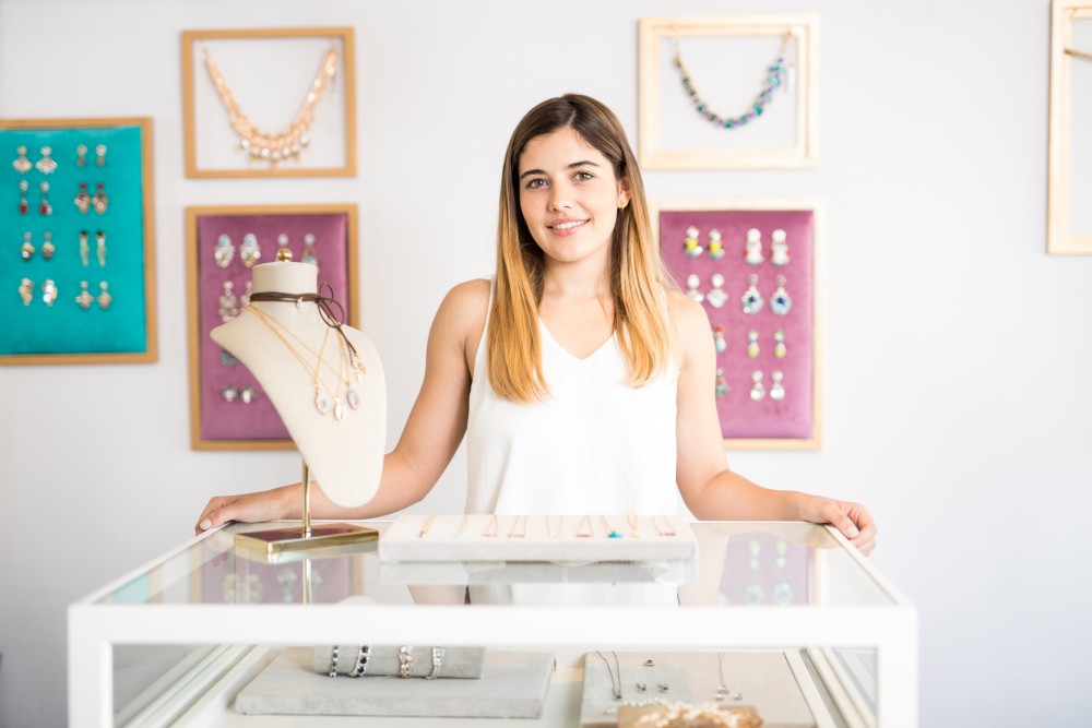 Portrait of a beautiful young Hispanic woman standing behind a counter in her jewelry shop and smiling